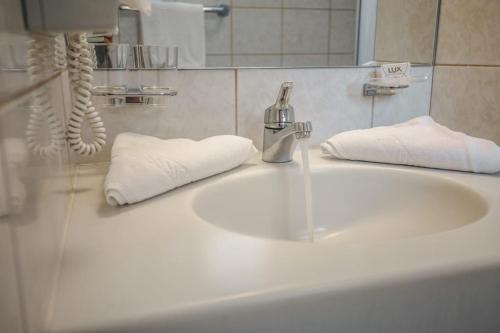 a bathroom sink with white towels and a faucet at Hotel Metzgerwirt in Kirchberg in Tirol