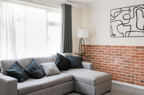un salon avec un canapé et un mur de briques dans l'établissement The House In Defoe Rd - 3br 1bath W Free Parking, à Ipswich