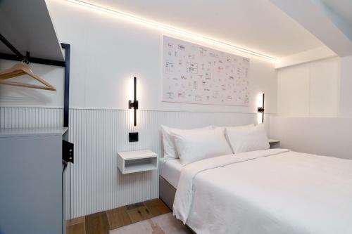 a bedroom with a white bed and a white wall at Casa Guogu by AmazINN Places 3f in Panama City