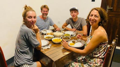 a group of people sitting around a table eating food at Millenium Lodge - Anuradhapura in Anuradhapura