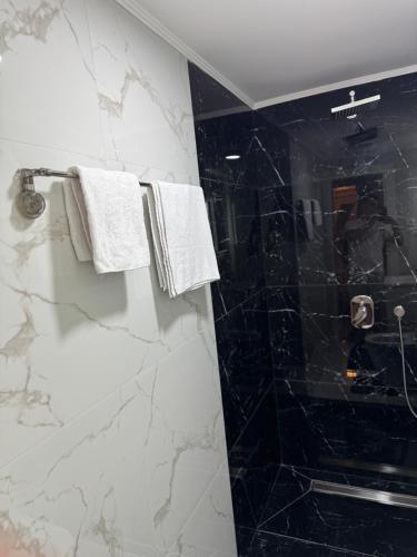 a bathroom with black and white marble walls and towels at Apartman Đak in Foča