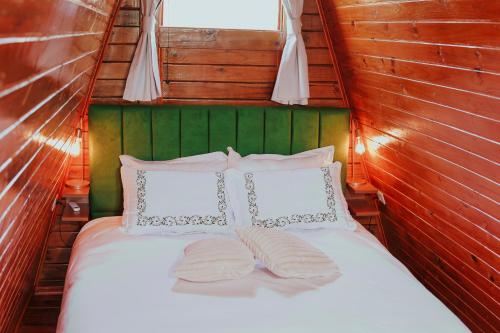 a bed with two pillows on top of it at Chalé Refúgio da Coruja in Miracatu