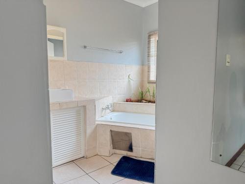 a white bathroom with a tub and a sink at De'Lush Oasis in Pretoria