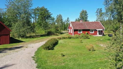 a red house in a field next to a dirt road at Holiday home Småland Siggamåla in Husjönäs