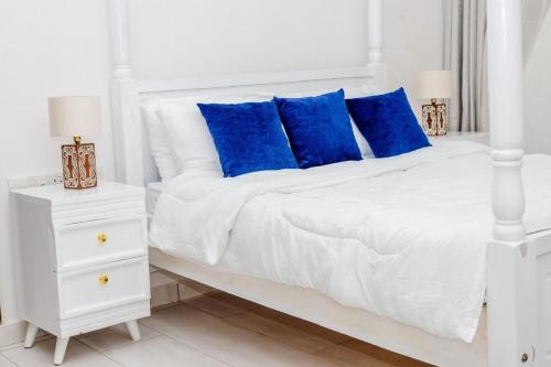 乌昆达LILAC Beachfront 1bedroom Apartment的一张白色的床，配有蓝色的枕头和白色的床头柜