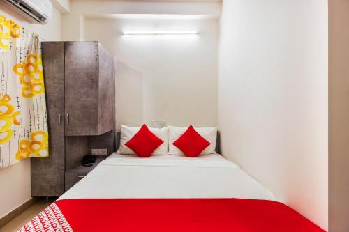 a bedroom with a bed with red pillows at Hotel O D' Jade in Hyderabad