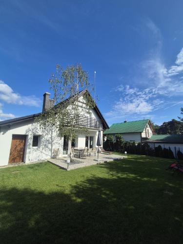 a white building with a grass yard in front of it at Przystanek Osłonin- całoroczny dom na wynajem in Osłonin