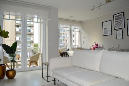 a living room with a white couch and a balcony at Modern appartement met doorkijk op de duinen in Cadzand