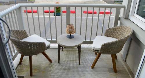 three chairs and a table on a balcony at Modern appartement met doorkijk op de duinen in Cadzand