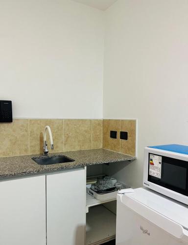 a kitchen with a sink and a microwave at Monoambiente Compacto con Patio - Equipado para 3 huéspedes in Buenos Aires