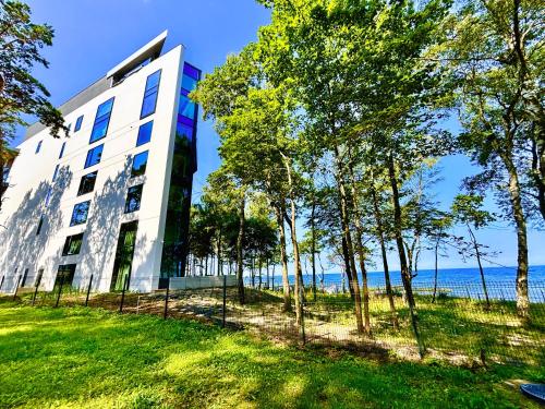 un edificio con árboles frente al agua en Baltic Jet Ustronie Morskie, en Ustronie Morskie