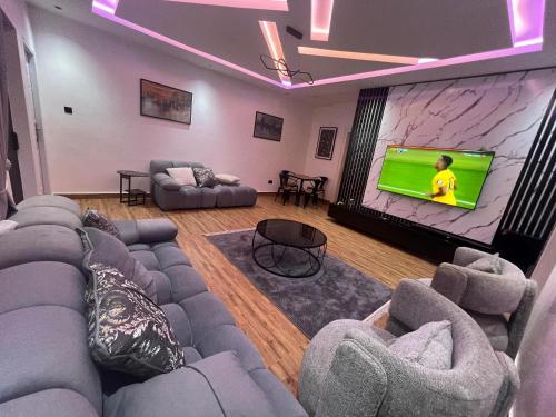 a living room with couches and a large screen tv at MedeHeights Apartments in Abuja