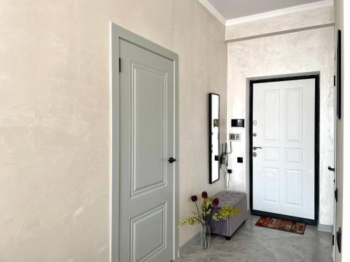 a hallway with a white door and a vase of flowers at Уютные Апартаменты 1 Минута от Станции Метро in Almaty
