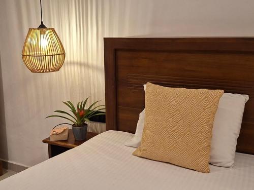 a bedroom with a bed with a wooden headboard and a lamp at Naolina Beach Villa in Weligama