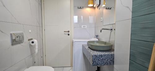 a white bathroom with a sink and a toilet at ATLANTIC Apartments in Štip