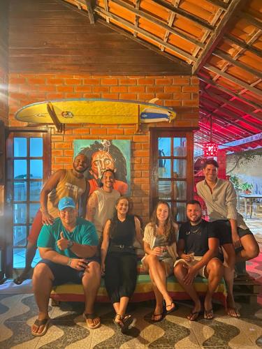 a group of people sitting on a bench in front of a painting at Canoa Roots Hostel & Camping in Canoa Quebrada