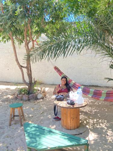 a woman sitting in a hammock under a tree at Canoa Roots Hostel & Camping in Canoa Quebrada