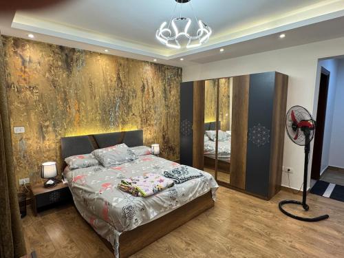 a bedroom with a bed and a wall with a painting at Cozy Super Furnished Fully equipped and decorated in 6th Of October