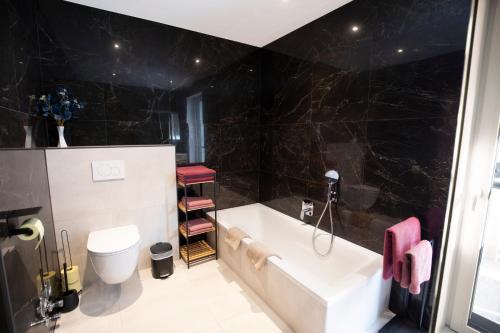 a bathroom with a bath tub and a toilet at Alpin Apartments Volderauer in Neustift im Stubaital