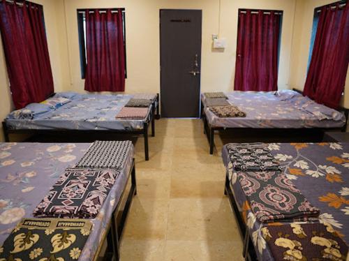 four beds in a room with red curtains at Ganraj River Rafting Kolad in Kolād