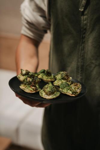 a person is holding a plate of broccoli at MIRA Earth Studios in Valle de Guadalupe