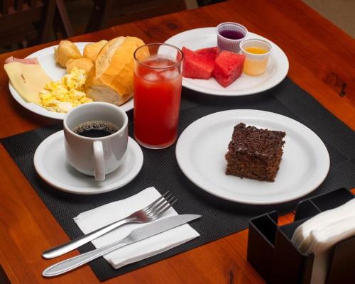 a table with three plates of food and a drink at Buriti Hotel Aracruz in Aracruz