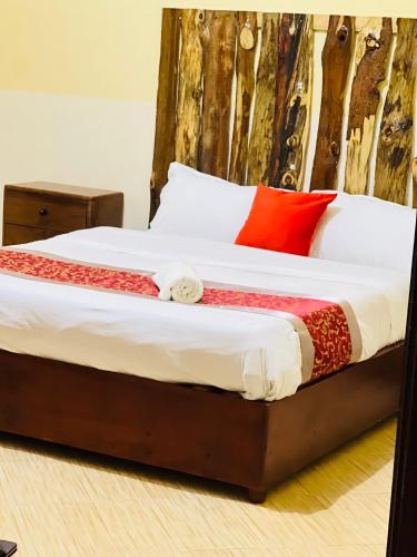 a bed with white sheets and red pillows at Nura Apartments in Kisoro