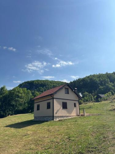a small white house on a hill in a field at Silence of the Forest in Foča