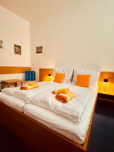 a large white bed with orange pillows on it at Penzion Ludor in Strážnice