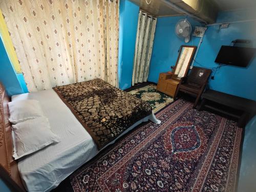 a bedroom with a bed and a chair and a television at Lake Boulevard Guest House in Srinagar