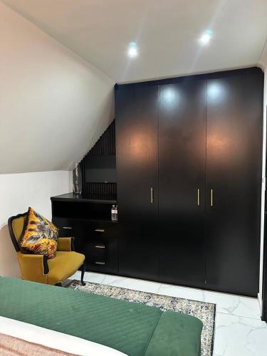 a bedroom with a bed and a chair and a cabinet at Maison Norelle at Isivuno House in Gillitts