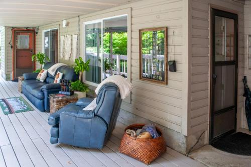 a porch with two blue chairs on a house at The Owls Nest with Hot Tub and Forest Views! in Portland