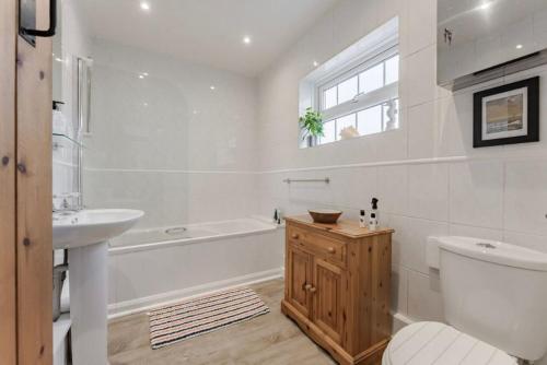 La salle de bains blanche est pourvue d'une baignoire, d'un lavabo et de toilettes. dans l'établissement Chalk Reef Cottage - Sheringham Cottages, à Sheringham