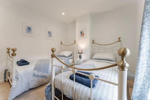 deux lits jumeaux dans une chambre aux murs blancs dans l'établissement Chalk Reef Cottage - Sheringham Cottages, à Sheringham