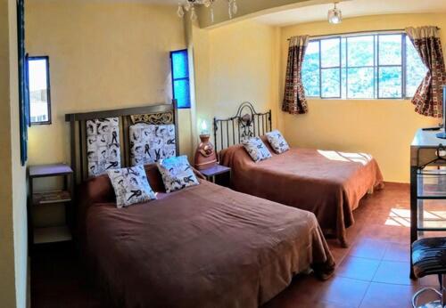 a bedroom with two beds and a window at Hotel Posada Spa Antigua Casa Hogar in Taxco de Alarcón