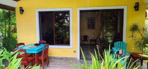 a yellow house with a blue table and chairs at Villa Colibri at LakeGardens in Nuevo Arenal