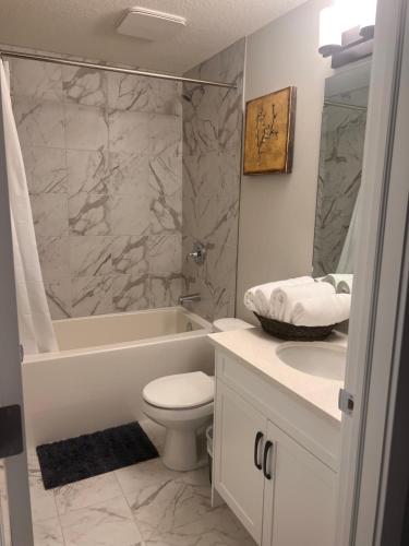 a bathroom with a toilet and a tub and a sink at Guest Suite in Southwest Calgary in Calgary
