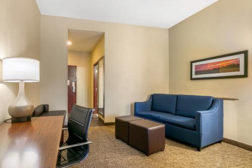 a living room with a blue couch and a table at Comfort Suites in Forrest City