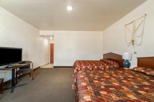 a hotel room with a bed and a desk and a television at Hotel O Colonial Inn Brownsville Tx in Brownsville
