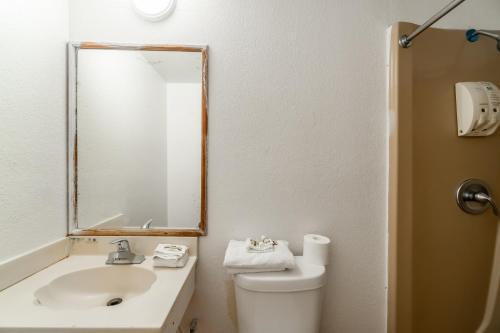 a bathroom with a sink and a toilet and a mirror at Hotel O Colonial Inn Brownsville Tx in Brownsville