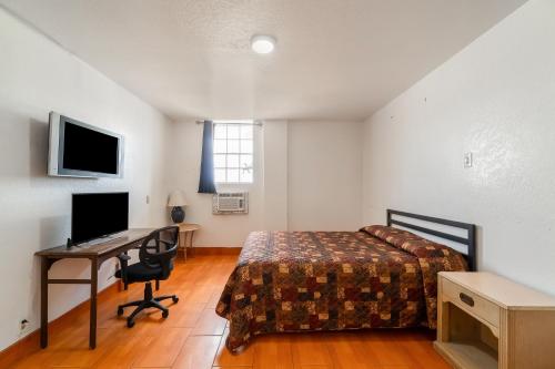 a bedroom with a bed and a desk with a computer at Hotel O Colonial Inn Brownsville Tx in Brownsville
