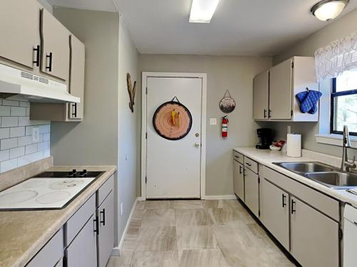 a kitchen with white cabinets and a white door at Knotty Pines Cabin in Ruidoso