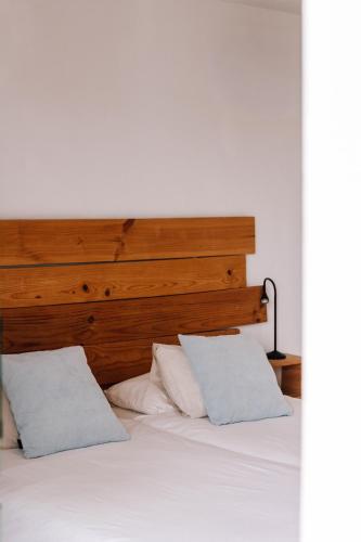a bed with a wooden headboard and two white pillows at Surfescape Fuerteventura in Lajares