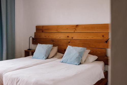 a bed with two blue pillows on top of it at Surfescape Fuerteventura in Lajares