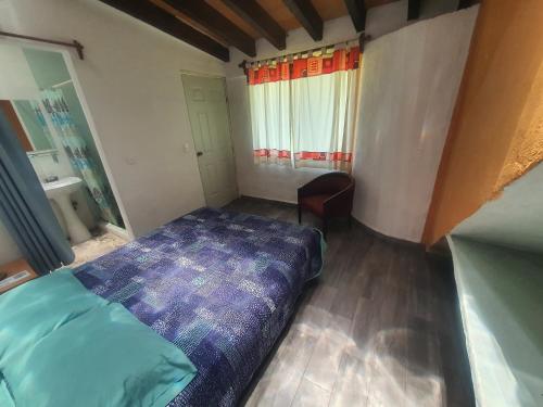 a small bedroom with a bed and a window at Ollin Calli Hostal-Temazcal in Tepoztlán