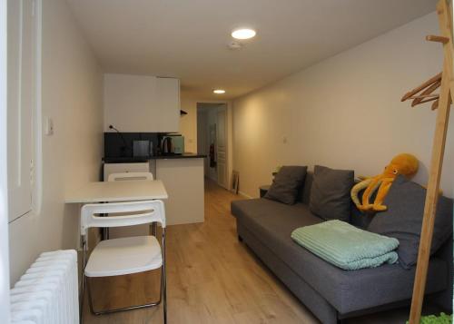 Una sala de estar con un sofá y una cocina. en Cosy New Studio 2 min RER B, en Aulnay-sous-Bois