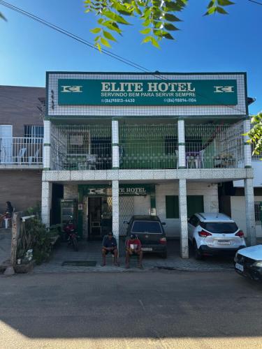 two men sitting in front of a blue hotel at Elite Hotel 02 in Teresina
