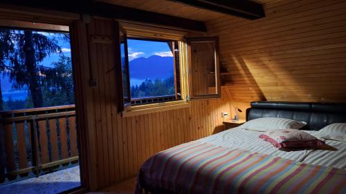 a bedroom with a bed and a balcony with windows at Apartma Jurjovka in Nazarje