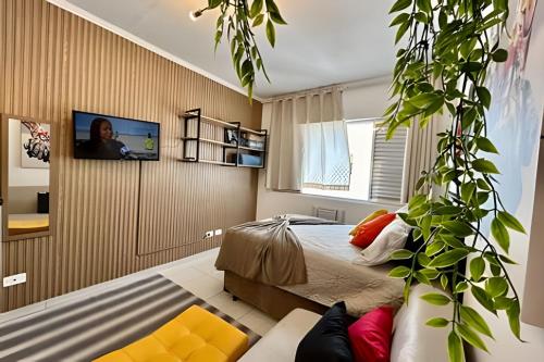 a bedroom with a bed and a tv on a wall at SHB - Studio in the Heart of Gonzaga by the Sea in Santos