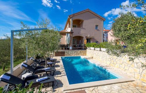 a swimming pool with lounge chairs and a house at Holiday apartment Boko in Pinezici